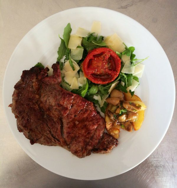 Entrecôte argentina con soncino di rucola scaglie e pomodori appassiti accostate a contorno di patate e porcini.